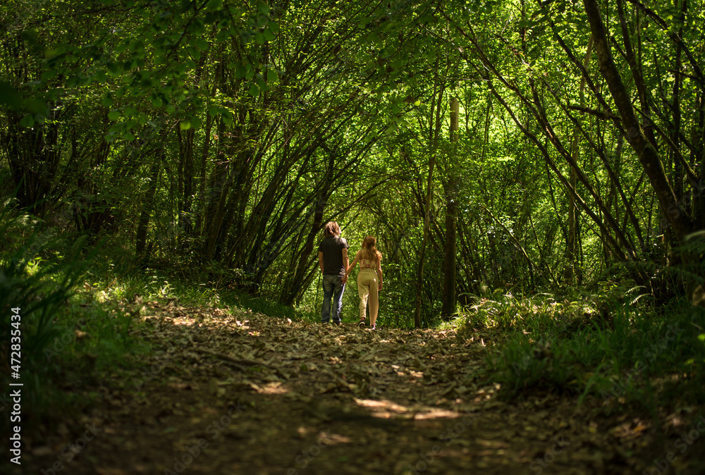 Young couple walking in green lush forest in national park Young couple walking in green lush forest in national park