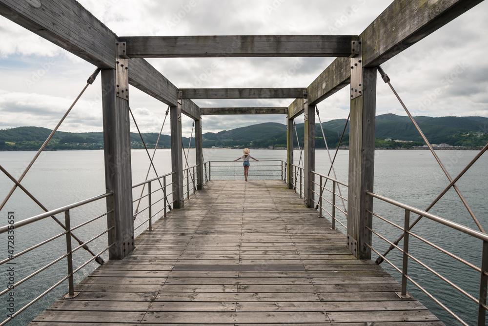Female traveler on wooden pier near sea Female traveler on wooden pier near sea
