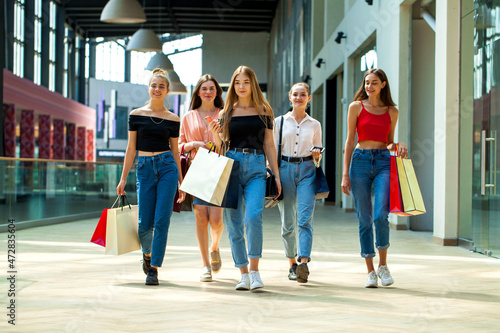 Five happy young women are walking in the mall