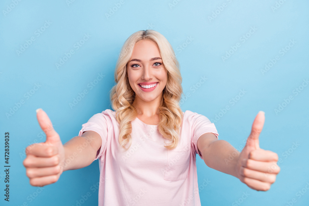 Photo of funky millennial blond lady show thumb up wear pink t-shirt isolated on blue color background Photo of funky millennial blond lady show thumb up wear pink t-shirt isolated on blue color background