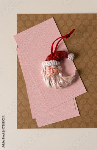 santa face christmas ornament on brown and pink paper background