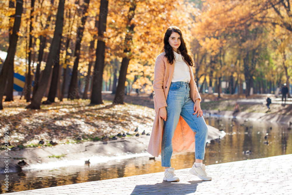 Portrait of a young beautiful brunette woman in autumn park