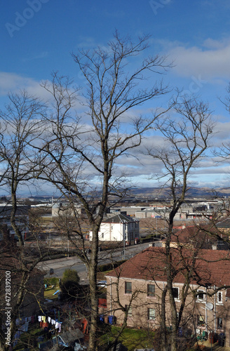 Landscape View of Distant Hills on Sunny Day seen above Buildings through Leafless Winter Trees 