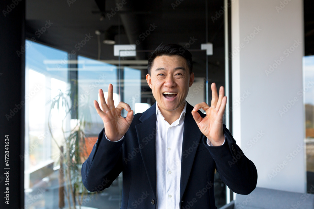 Portrait of successful business owner male boss asian cheerful happy smiling and rejoicing in modern office by big window