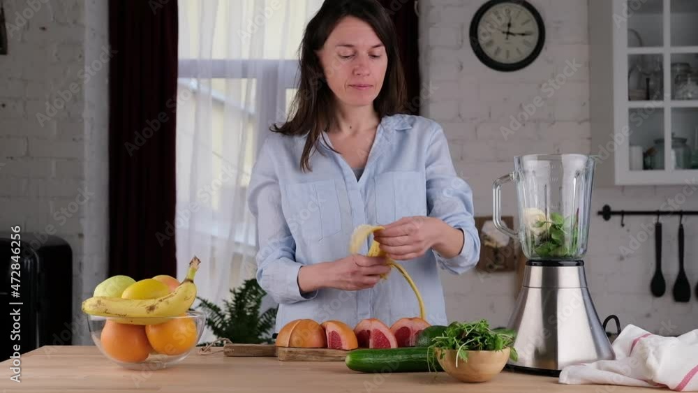 Young Woman Making Detox Smoothie At Home. Young woman cooking green smoothie with banana spinach and arugula. healthy food concept Young Woman Making Detox Smoothie At Home. Young woman cooking green smoothie with banana spinach and arugula. healthy food concept
