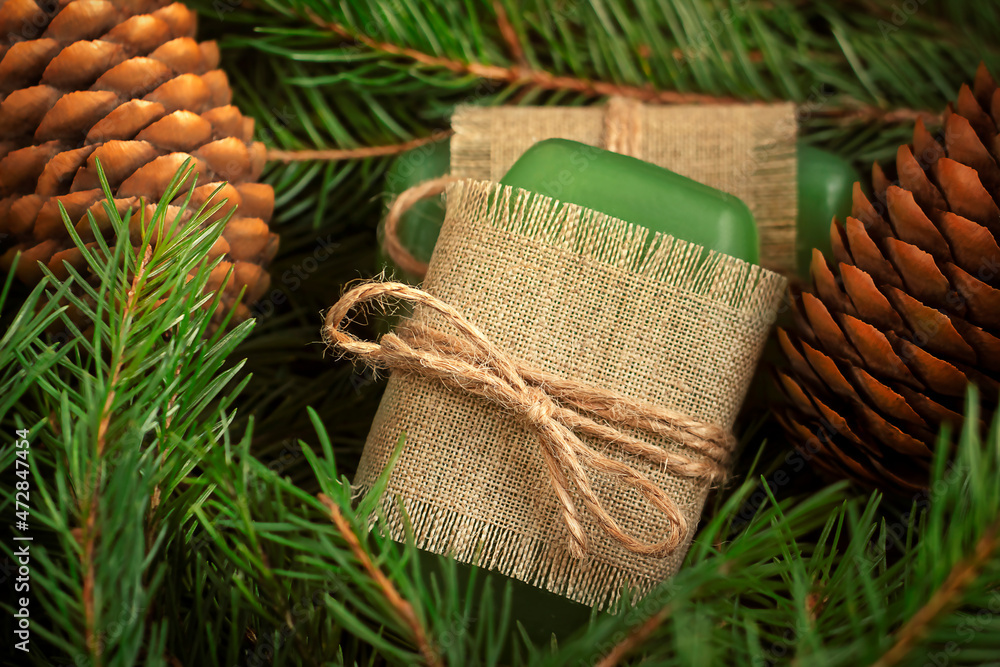 green soap made of environmentally friendly materials on a wooden background. Fir branches in the background