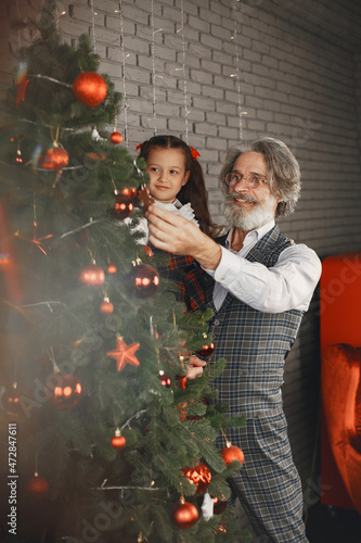 Smiling grandfather and granddaughter decorate the Christmass rtee photo