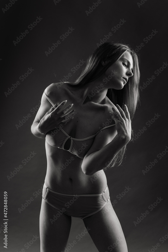 Fototapeta premium Glamorous woman with a seductive body and large breasts in lingerie on blue yellow studio background
