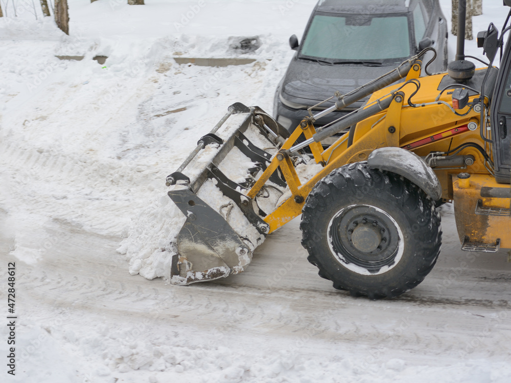 Tractor bulldozer clears snow in the parking lot for cars. Winter works Tractor bulldozer clears snow in the parking lot for cars. Winter works