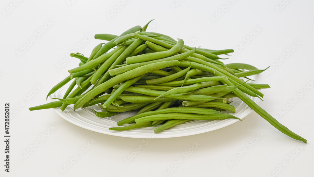 Fresh raw organic green beans in a bowl close up on white background Fresh raw organic green beans in a bowl close up on white background