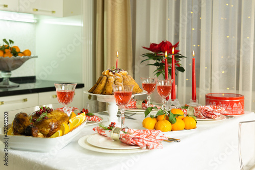 Beautifully decorated festive table with baked chicken, homemade cake, glasses of wine and candles. Baked chicken for Thanksgiving, Christmas and New Year.