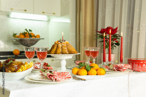 Beautifully decorated festive table with baked chicken, homemade cake, glasses of wine and candles. Baked chicken for Thanksgiving, Christmas and New Year.