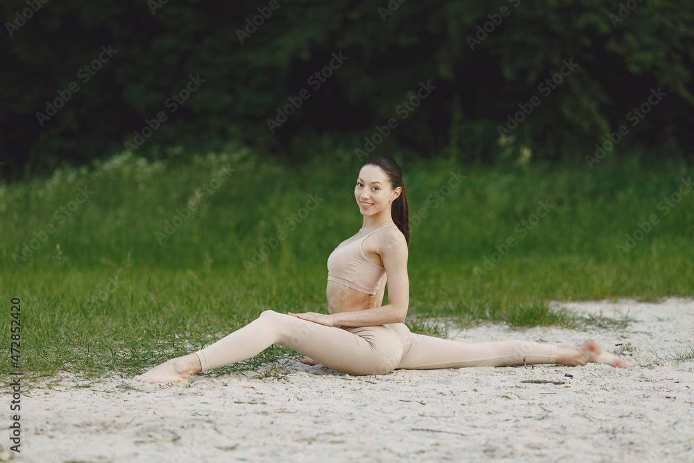 Fototapeta premium Woman practicing advanced yoga in a beach