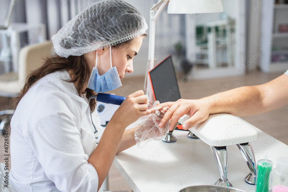 Obraz premium Girl manicurist doing manicure for man. Man professional manicure at the beauty spa salon. Male body care. Relaxing, caring about nails, spa treatment. Manicure specialist and client
