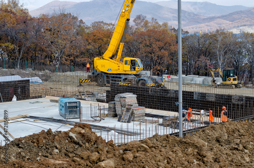 A construction crane in the center of a construction site with an erected foundation.