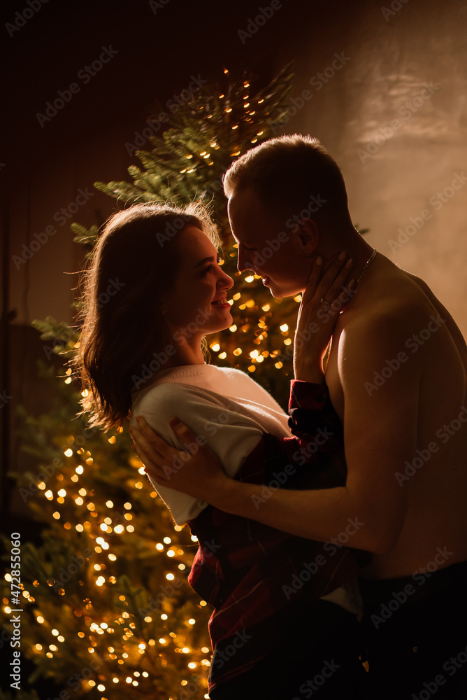 Young guy kissing his lovely girlfriend feeling happiness while celebrating winter holidays together