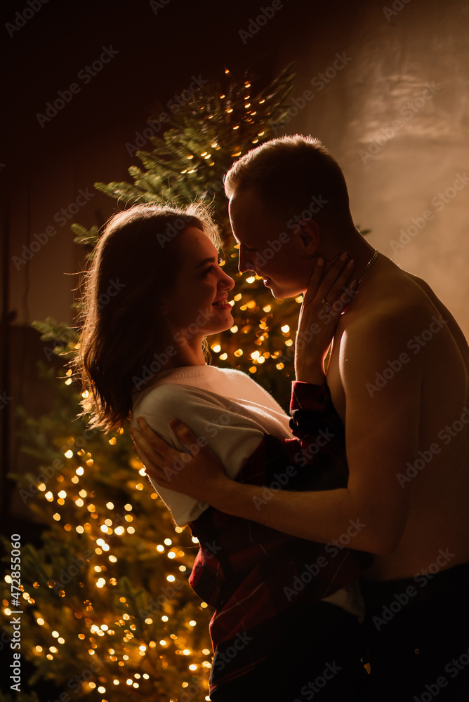 Young guy kissing his lovely girlfriend feeling happiness while celebrating winter holidays together Young guy kissing his lovely girlfriend feeling happiness while celebrating winter holidays together