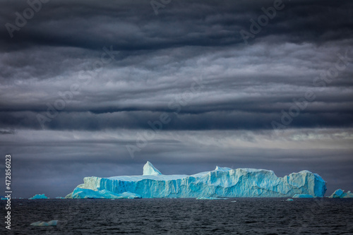 Huge iceberg floating in the sea under dark stormy sky: Disko Bay, Greenland photo
