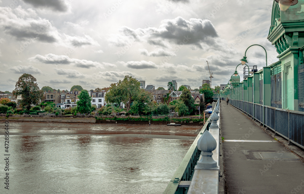 The Fulham Railway Bridge that spans river Thames, seen from the north. Colloquially known as The Iron Bridge, it can also be crossed on foot. Putney is in the background.