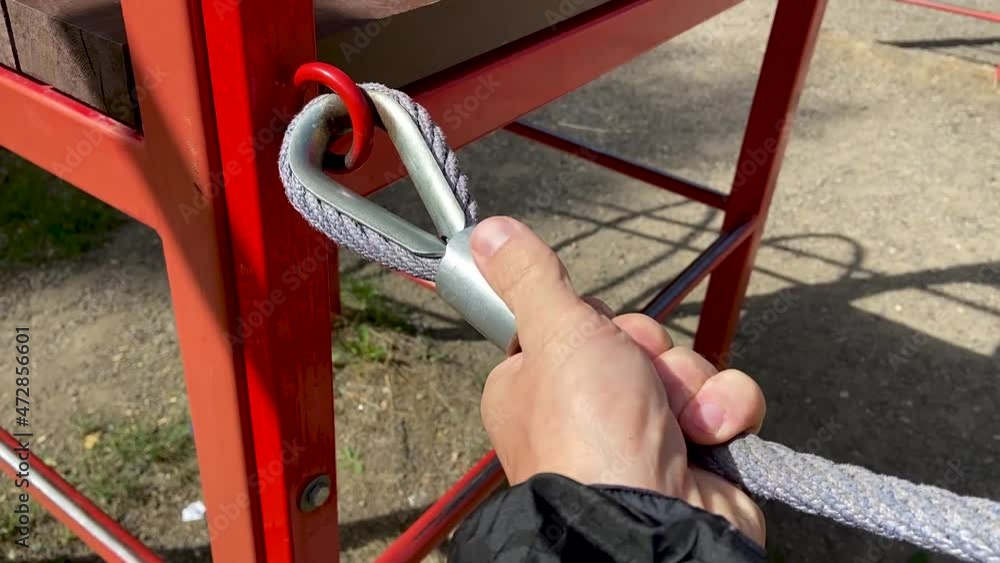 man checks the reliability of a child's rope net 