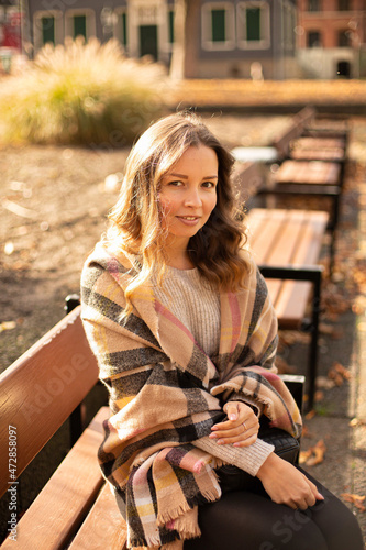 European white young woman with brown hair sitting on bench in sunny autumn