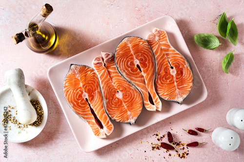 slices of fresh salmon in a pink plate on a pink table, ready to cook photo