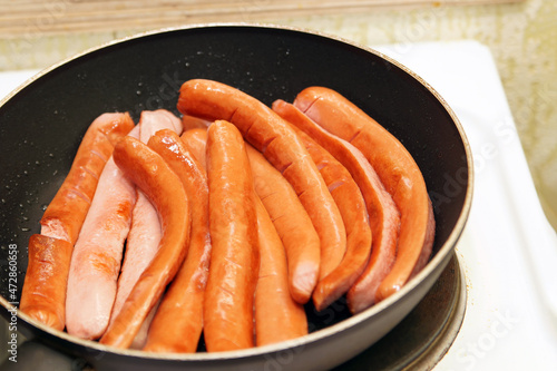 Sliced thin sausages are fried on a scoop.