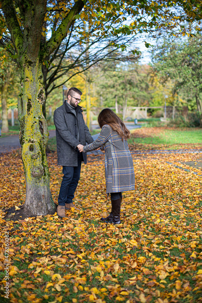 White young european man and woman with dark hair holding hands in autumn forest