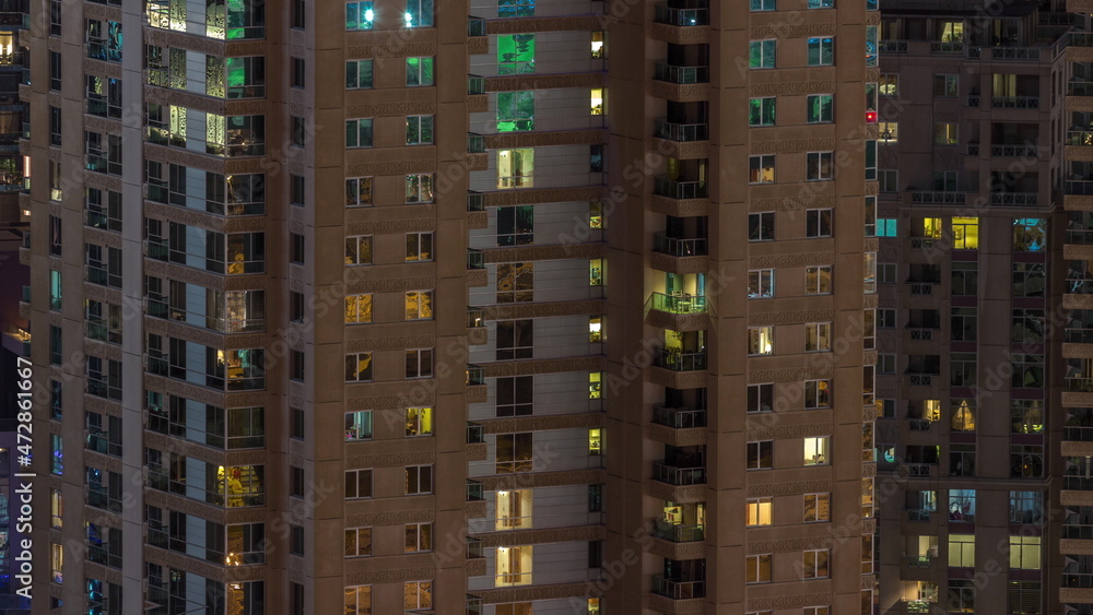 Windows in high-rise building exterior in the late evening with interior lights on timelapse
