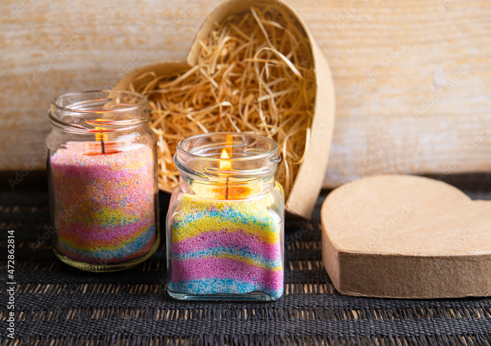 Young children making fun colorful layered granulated wax candles in home  by pouring powder in old baby food jar and inserting wick inside. Hobby  concept. Stock Photo