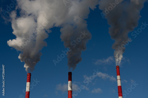 industrial chimneys with heavy smoke causing air pollution on the blue sky background