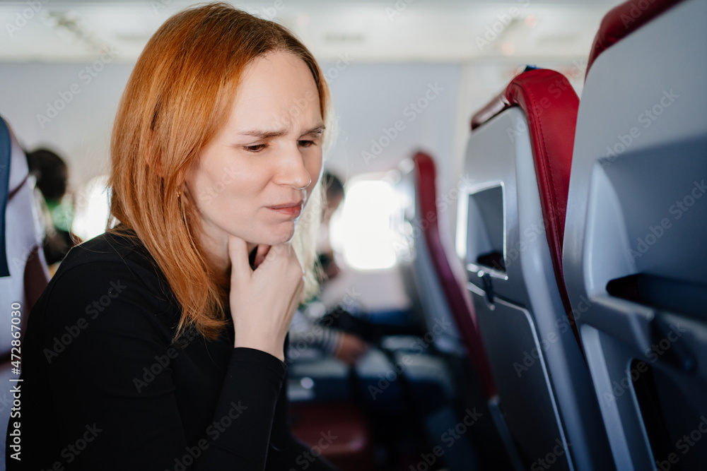 a cold woman coughs up a sore throat flying on an airplane. a cold woman coughs up a sore throat flying on an airplane.