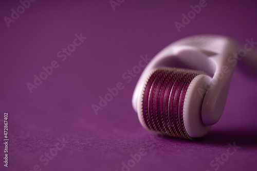 cosmetic face roller on purple background photo