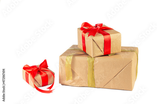 Gift box wrapped in Kraft paper with red and golden ribbon on white background. Holiday or Christmas gift boxes background. © Natia
