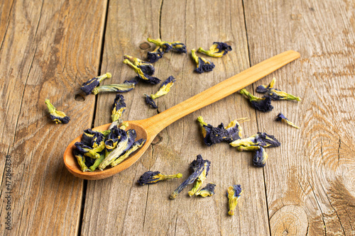 Lot of whole dry clitoria ternatea in a wooden spoon on old wood