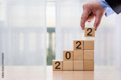 Businessman who looks forward confidently and turns calendar dates into years 2021, the concept of a man happily holding a wooden block with the number of years that change across.