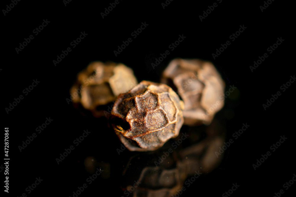Group of three whole spicy black pepper isolated on black glass Group of three whole spicy black pepper isolated on black glass