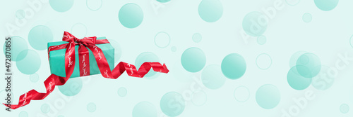 Background with a gift. A blue gift box with a red satin ribbon.