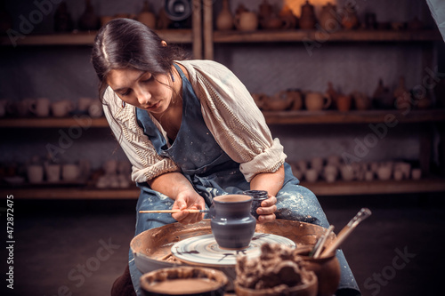 Young female potter working on a potter's wheel. photo