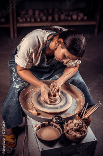 Beautiful artisan girl making pottery, sculptor from wet clay on wheel. Concept for woman in freelance, business, hobby. photo