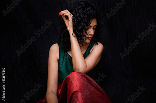 A women wearing green and red dress with curly hair photo