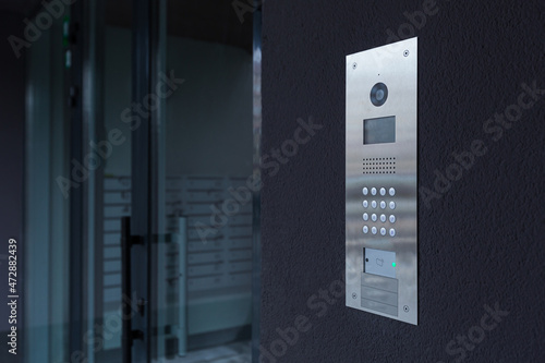 Entrance doorbell in a multi-apartment building, with a video surveillance camera, on a dark wall photo