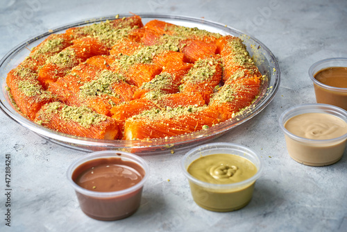 Arabian Traditional Desserts rolls - Cream and cheeses with pistachio flavor and nuts topping on gray background