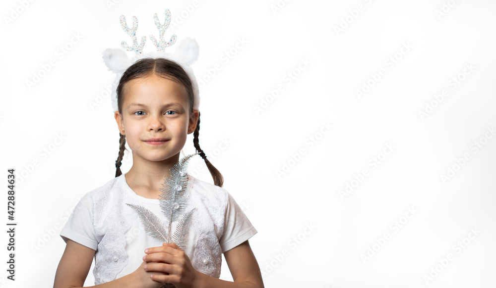 Portrait of smiling little girl in Christmas deer headband holding silver Christmas decoration against white background Portrait of smiling little girl in Christmas deer headband holding silver Christmas decoration against white background