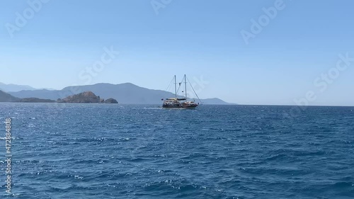 A seagoing ship is sailing on the sea. Ship at sea at full speed. The yacht sails near the island. 12-island tour from Oludeniz - Fethiye, Turkey, August 10, 2021. photo