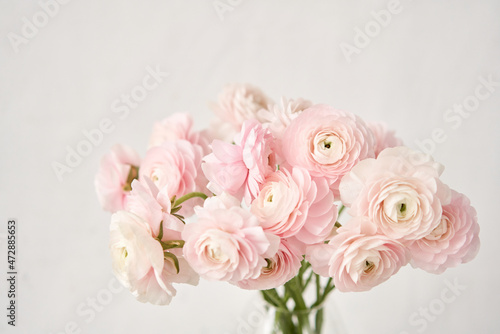 The background of ranunculus colors is gently pink. A riotous peony-shaped rose bouquet