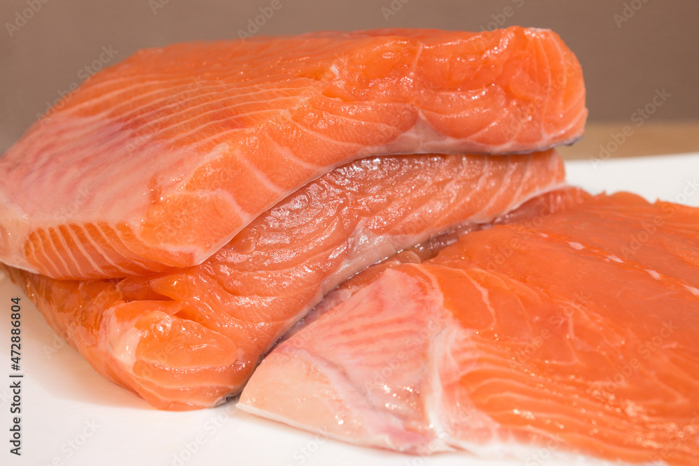 Close-up of fresh-cut salmon loins piled on a flat plate with creative blur. Healthy food ingredients. Nutrition and fish.