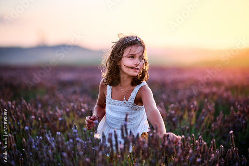 White Hispanic girl playing among lavender in the sunset sun