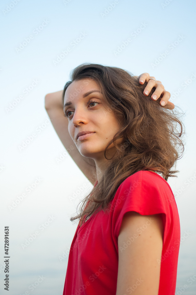 Young girl in red dress on the sea and blue background, summertime, travelling concepts Young girl in red dress on the sea and blue background, summertime, travelling concepts