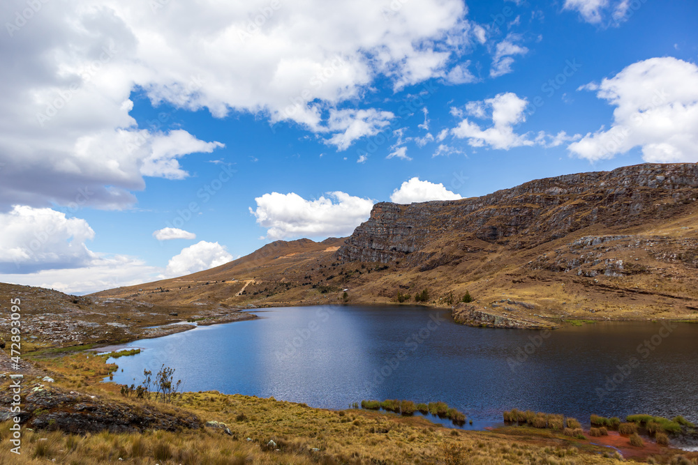 Wide view of the lake under the sky surrounded by an Andean ecosystem.
